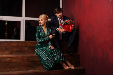 Young man and woman sitting on the stairs with the bouquet of flowers