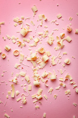 White chocolate curls on color background, top view