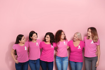 Group of women with silk ribbons on color background. Breast cancer awareness concept