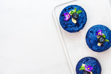 homemade raw blueberry and butterfly pea flower vegan cakes with fresh berries, mint, nuts. healthy vegan food concept