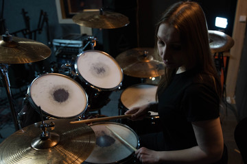 Professional drum set closeup. Beautiful young girl drummer with drumsticks playing drums and cymbals, on the live music rock concert or in recording studio   