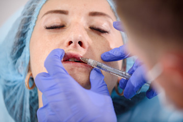 girl do plastic operation in medical clinic; doctor does lip augmentation surgery; injecting...