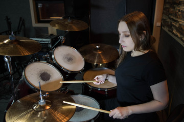 Professional drum set closeup. Beautiful young girl drummer with drumsticks playing drums and cymbals, on the live music rock concert or in recording studio   