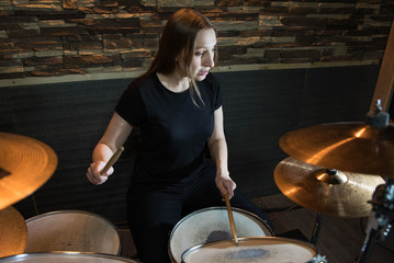 Professional drum set closeup. Beautiful young girl drummer with drumsticks playing drums and...