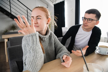 Fototapeta premium Arguing couple sitting apart at home. Young sad woman thinking about reconciliation with boyfriend.
