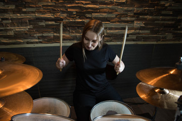 Professional drum set closeup. Beautiful young girl drummer with drumsticks playing drums and...