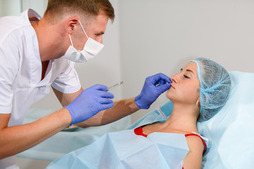 girl do plastic operation in medical clinic; doctor does lip augmentation surgery; injecting...