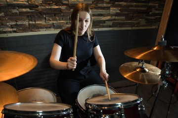 Obraz premium Professional drum set closeup. Beautiful young girl drummer with drumsticks playing drums and cymbals, on the live music rock concert or in recording studio 