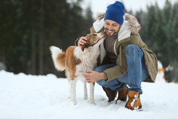 Man with cute dog near forest. Winter vacation