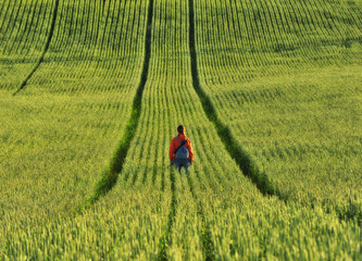 girl in the field. hilly spring field. tourist meditates in the field. Alone with nature