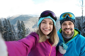 Fototapeta na wymiar Happy couple taking selfie during winter vacation in mountains