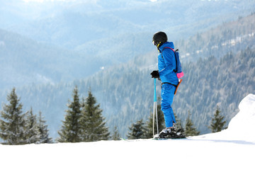Fototapeta na wymiar Man skiing on snowy hill in mountains, space for text. Winter vacation