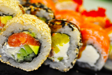 Eating Sushi with chopsticks. Sushi roll japanese food in restaurant. California Sushi roll set with salmon, vegetables, flying fish roe and caviar closeup. Japan restaurant menu