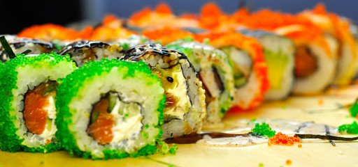 Eating Sushi with chopsticks. Sushi roll japanese food in restaurant. California Sushi roll set with salmon, vegetables, flying fish roe and caviar closeup. Japan restaurant menu