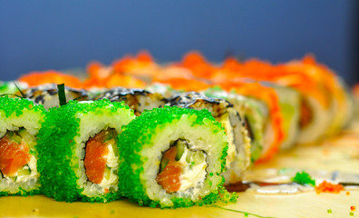 Eating Sushi with chopsticks. Sushi roll japanese food in restaurant. California Sushi roll set with salmon, vegetables, flying fish roe and caviar closeup. Japan restaurant menu