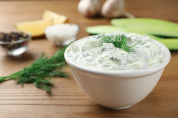 Obraz na płótnie Canvas Cucumber sauce with ingredients on wooden background, space for text. Traditional Tzatziki