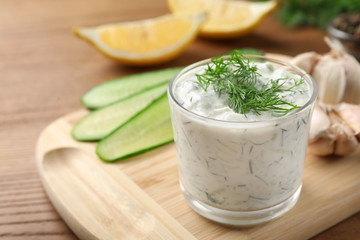Cucumber sauce with ingredients on wooden background, space for text. Traditional Tzatziki