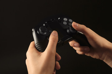 Woman holding video game controller on black background, closeup © New Africa