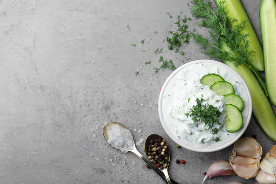 Cucumber sauce with ingredients on grey background, flat lay. Space for text