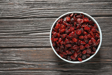 Bowl with cranberries on wooden background, top view with space for text. Dried fruit as healthy snack
