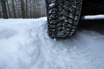 Snowy country road with car on winter day, closeup. Space for text