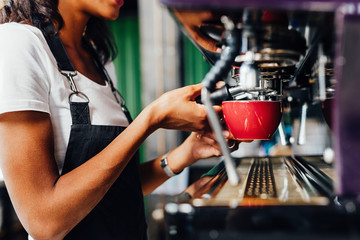 Unrecognizable female barista using a coffee maker to prepare a espresso