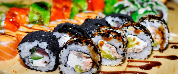 Eating Sushi with chopsticks. Sushi roll japanese food in restaurant. California Sushi roll set with salmon, vegetables, flying fish roe and caviar closeup. Japan restaurant menu