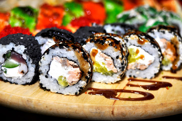 Eating Sushi with chopsticks. Sushi roll japanese food in restaurant. California Sushi roll set with salmon, vegetables, flying fish roe and caviar closeup. Japan restaurant menu