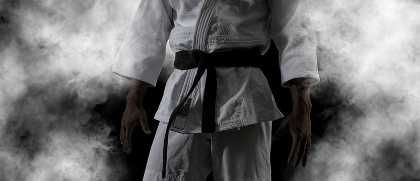 Guy poses in white kimono with black belt.  Black retouch