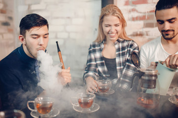 Rest in hookah, man makes tornado out of smoke shisha, friends watch and make photos