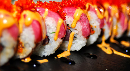 Eating Sushi with chopsticks. Sushi roll japanese food in restaurant. California Sushi roll set with salmon, vegetables, flying fish roe and caviar closeup. Japan restaurant menu