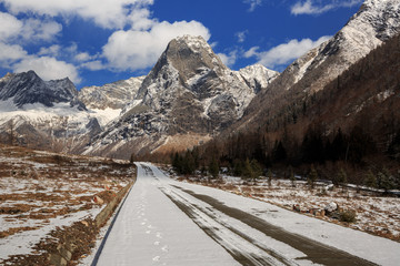 Fototapeta na wymiar ShuangQiao Valley Scenic Area, Four Girls Mountain National Park in Sichuan Province China. Snow Capped Jagged Mountains and Blue Sky, Snow Mountains, Empty National Park Utility Access Road