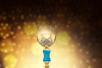 Close-up human hand holding golden Trophy on blurred  background