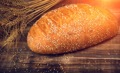 Fresh fragrant bread on a wooden table at sunset. Homemade hot pastry with.