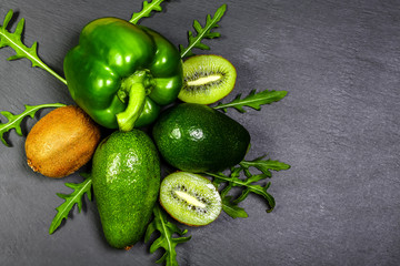 Group of green vegetables and fruits on a grey stone background. Copy space Top view