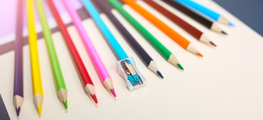 Colour pencils with sharpener lying on pastel beige background. Back to school concept. Colorful art studying and painting process. Drawing with pencils. Copy space place for postcard wish.