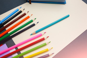 Fototapeta premium Colour pencils with notebooks and lying on pastel beige background. Back to school concept sign written. Colorful art studying and painting process.