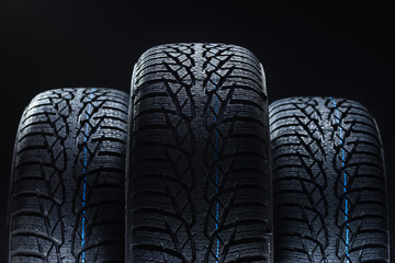 Set of new winter tires on black background with contrasty lighting. Close up product photograph of...