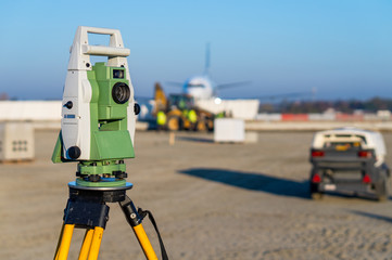 Surveyor equipment (theodolite) on construction site of the airport, building or road with construction machines in background