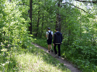 two young people traveling on a forest road between the trees