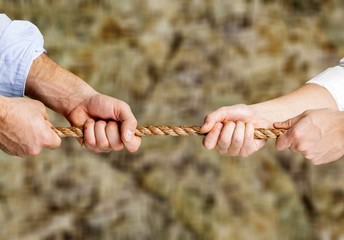 Business people pulling rope in opposite directions at office