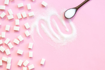 White sugar with spoon on pink background.