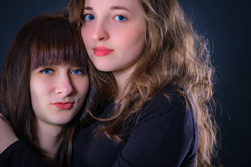 Naklejka premium Group portrait of two girls on a dark background