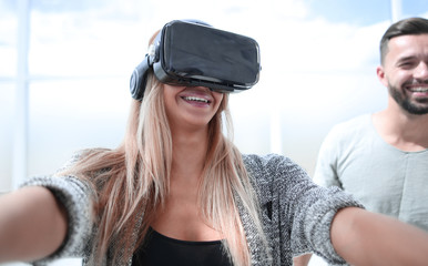 Girl in VR glasses of virtual reality with gamepad playing game