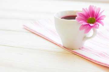 Black tea ceremony - a cup of tea, teapot, sugar, cakes, flowers on white wooden rustic background