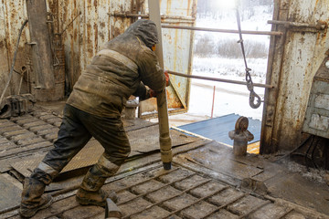 Offshore oil rig worker prepare tool and equipment for perforation oil and gas well at wellhead platform. Making up a drill pipe connection. A view for drill pipe connection from between the stands.