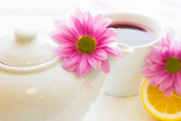 Fototapeta na wymiar Black tea ceremony - a cup of tea, teapot, sugar, cakes, flowers on white wooden rustic background