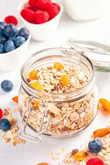 Jar with homemade granola or oatmeal muesli with nuts, dried fruits and fresh berries. Healty diet breakfast, vegan or vegeterian food concept