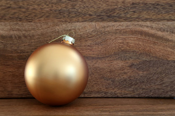 one golden Christmas bauble against wooden background