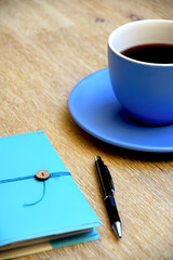 Black coffee, pen and notebook on table